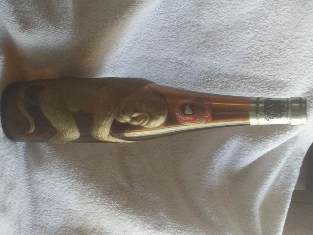 Old brown German bottle with gold embossed monkey wrapped around it