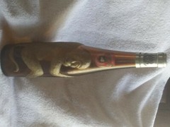 Old brown German bottle with gold embossed monkey wrapped around it