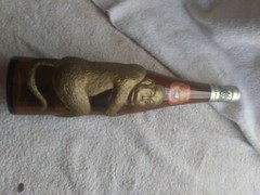 Old brown German bottle with gold embossed monkey wrapped around it