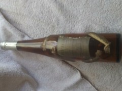 Old brown German bottle with gold embossed monkey wrapped around it