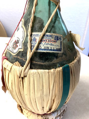 1951 Chianti Melini empty wine bottle, in wicker basket, with import stamp